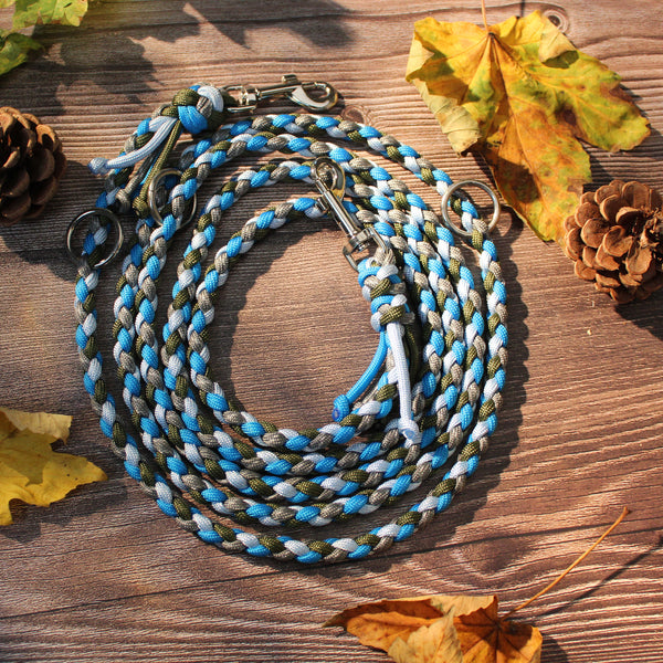 Paracord-Hundeleine Ljus in Blau, aufgerollt auf Holz, mit Karabinern und Ringen.