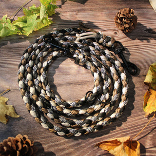 Paracord-Hundeleine Tjock in Braun, aufgerollt auf Holz, mit Karabinern und Ringen.