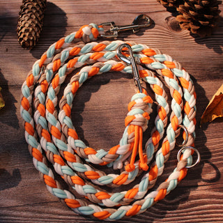 Paracord-Hundeleine Tjock in Orange, aufgerollt auf Holz, mit Karabinern und Ringen.